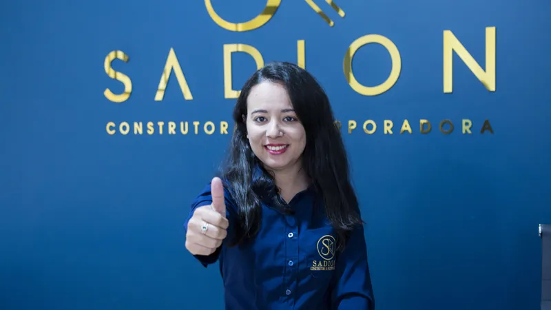 Consultora da Sadion fazendo sinal de positivo em frente ao logotipo